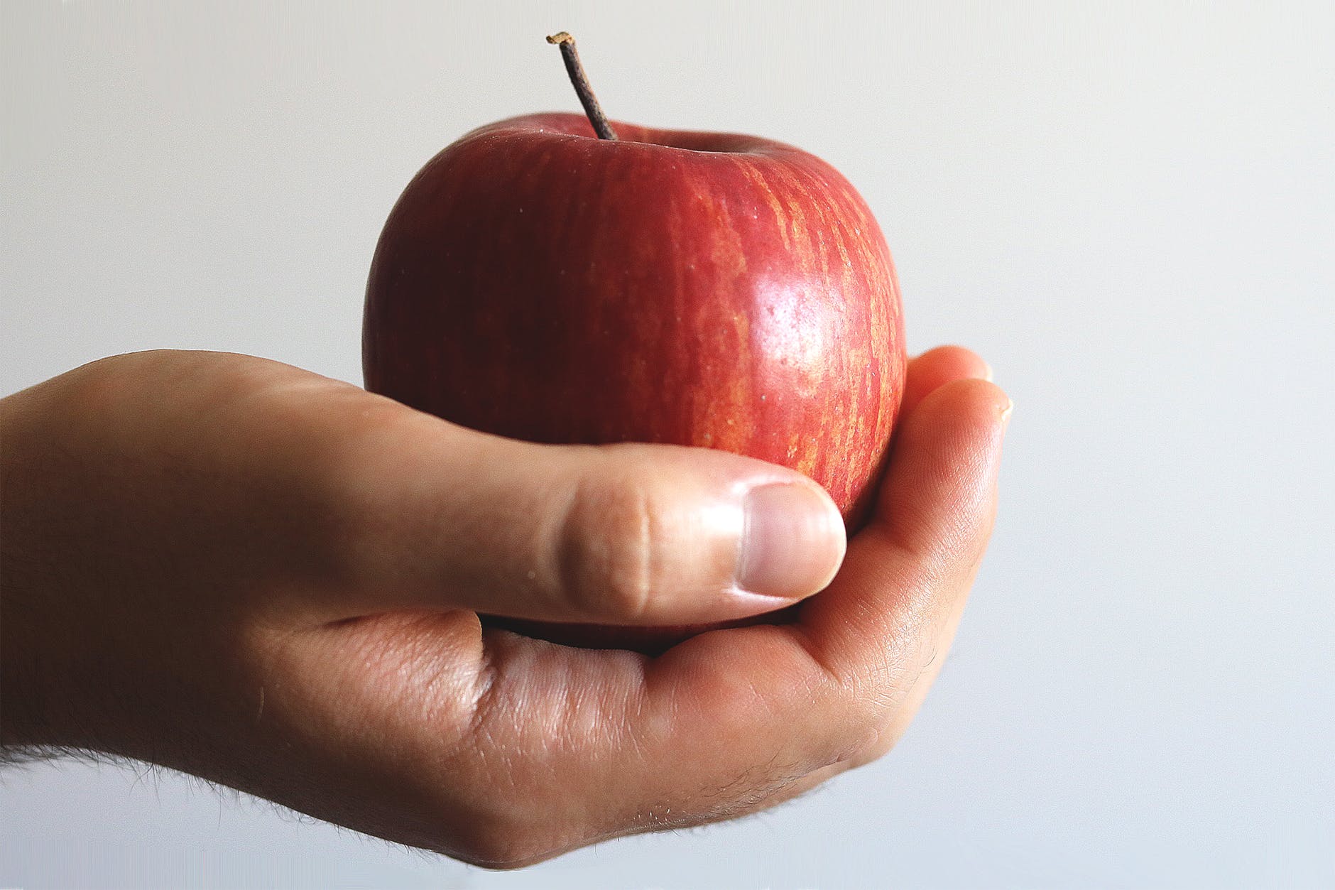 close up photo of person holding red apple