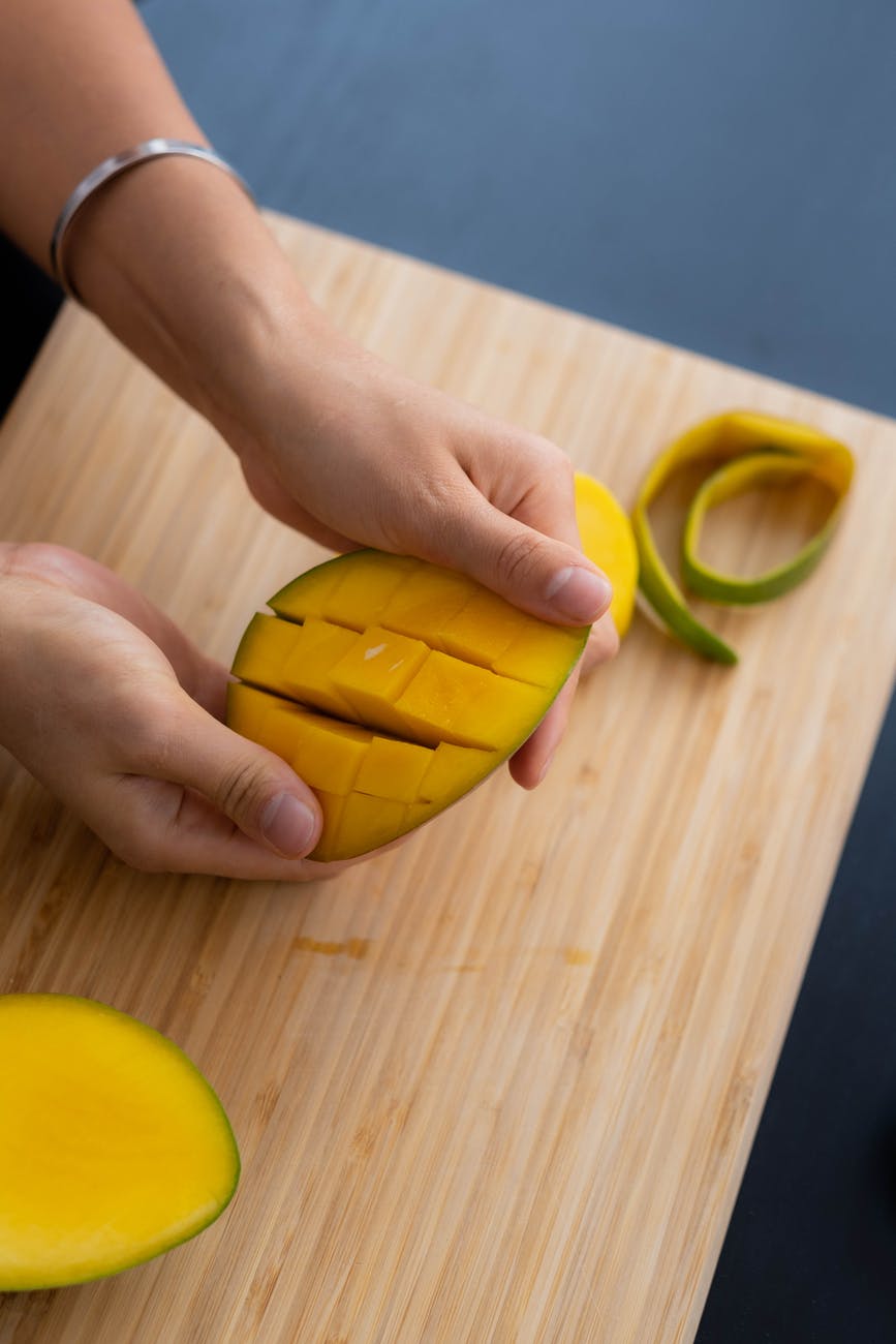 person holding a slice of mango